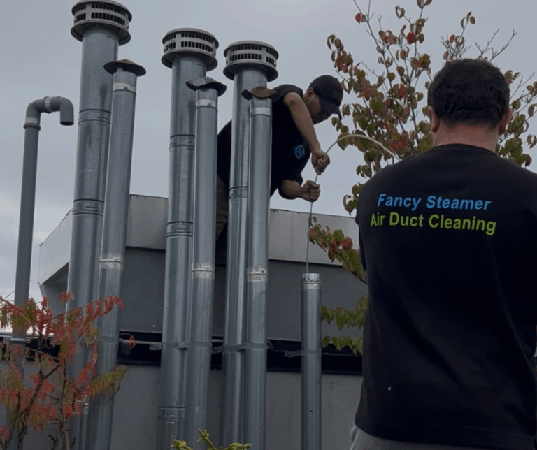 Two technicians use specialized equipment to clean and clear a dryer vent, ensuring proper airflow and safety.